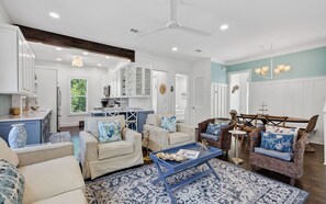 A spacious living room with a kitchen in the background, a dining area, and a large window with a view of greenery. - The Poppy House + Seaside, Pet Friendly & Bikes (Santa Rosa Beach)