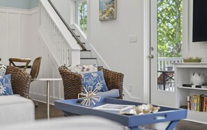 Una sala de estar con muebles de mimbre, una estantería y una escalera.