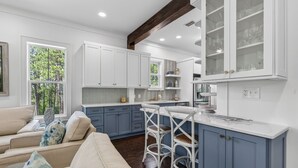 A modern kitchen with white cabinets, a bar area, and a dining space with a sofa. - The Poppy House + Seaside, Pet Friendly & Bikes (Santa Rosa Beach)
