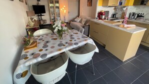 Una cocina moderna con una isla central, un comedor con mantel estampado y un salón con sofá.