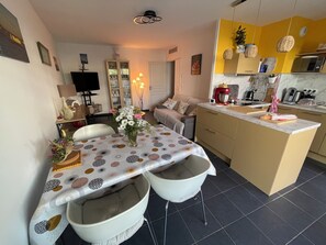 A modern kitchen with a central island, a dining area with a patterned tablecloth, and a living area with a sofa. - Quiet RDJ apartment, All amenities Porte Marine area (La Seyne-sur-Mer)