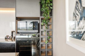 A kitchen with a built-in microwave, oven, and a vertical plant shelf. - Stylish 1BD Flat & Car Park, Deck + Harbour Views (Auckland)