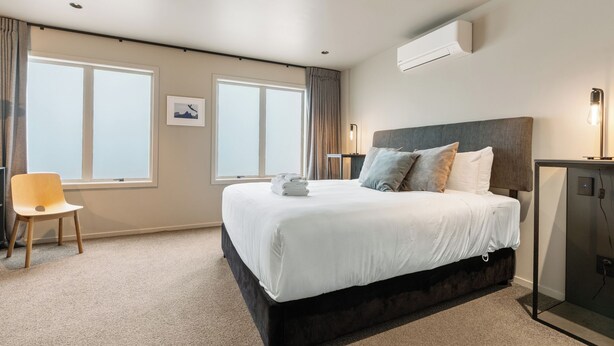 Een hotelkamer met een groot bed, een bureau, een stoel en een airconditioner.
