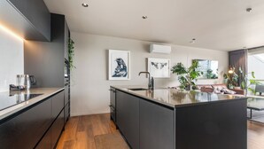 Een moderne keuken met een centraal eiland, donkere kastjes en een groot raam voor natuurlijk licht.
