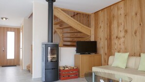 Ein modernes Wohnzimmer mit Kamin, Glastisch, Sofa und Fernseher.