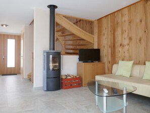 Ein modernes Wohnzimmer mit Kamin, Glastisch, Sofa und Fernseher.