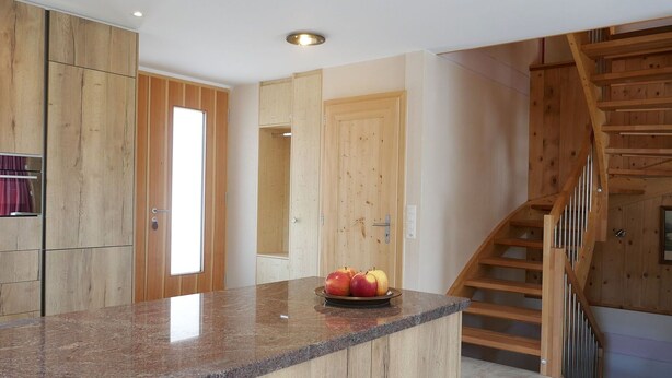 Eine Küche mit Holzschränken, einer Arbeitsplatte aus Granit und einer Obstschale.