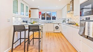 A modern kitchen with a washing machine, a Bosch oven, and a window with a view of buildings. - Cozy Family & Contractor Home, 3X FREE Parking by Redwood Stays (Hampshire)
