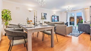 A modern dining area with a white table set for six, grey upholstered chairs, and a chandelier. - Cozy Family & Contractor Home, 3X FREE Parking by Redwood Stays (Hampshire)
