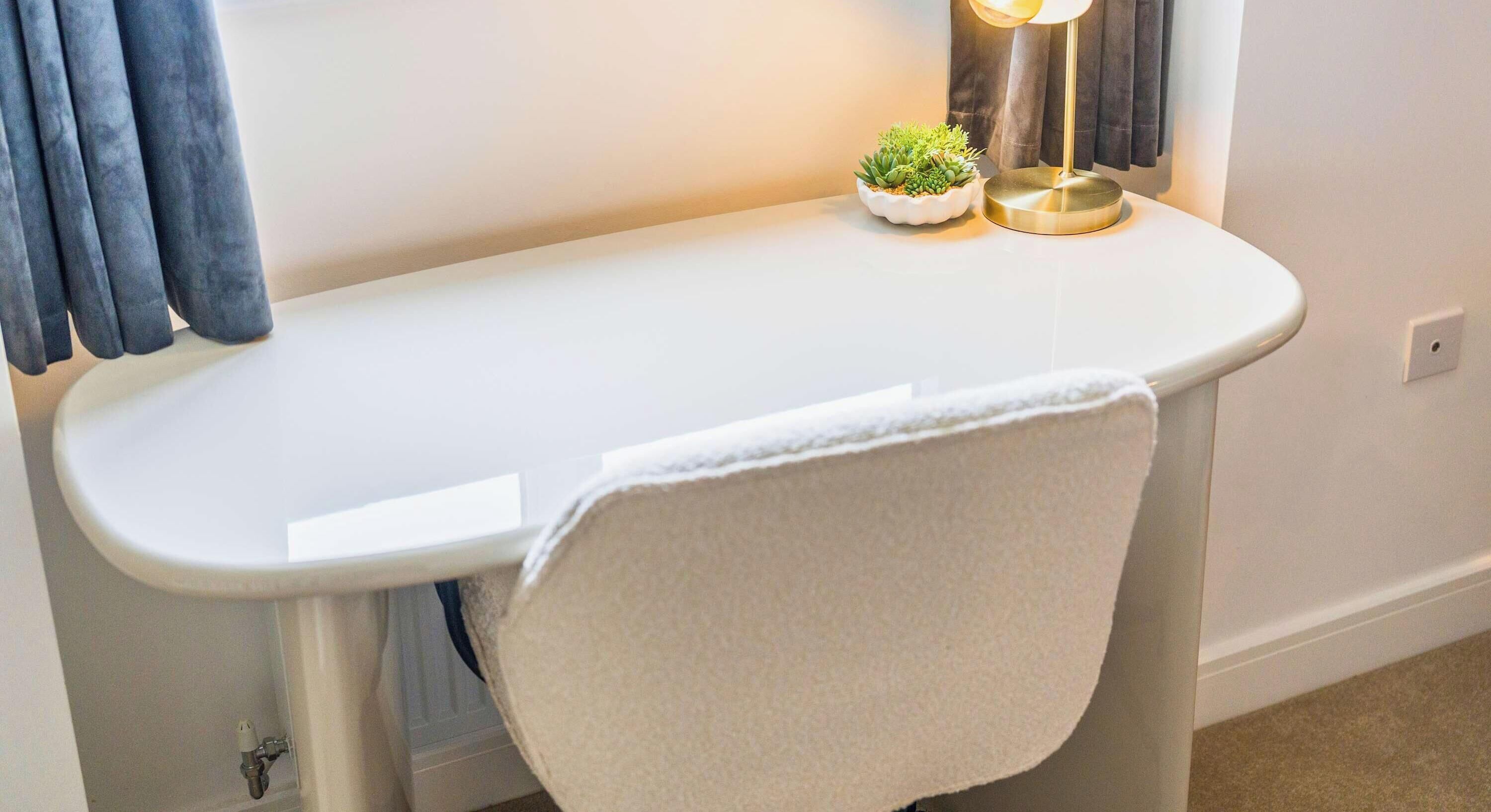 A white bathroom vanity with a towel hanging on the side, a small potted plant, and a floor lamp.