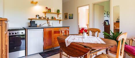 A compact kitchen with a stove, refrigerator, and wooden cabinets.