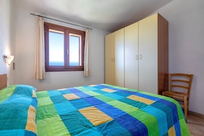 Een slaapkamer met een bed, een kledingkast, een stoel en een raam.