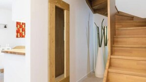 A hallway with a wooden door, a staircase, and a wall-mounted shelf with a red patterned object. - Pigneto Rooftop: Elegant Two-Level Penthouse with Spacious Terraces (Roma)