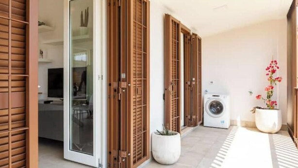 A corridor with sliding wooden doors, a washing machine, and potted plants. - Pigneto Rooftop: Elegant Two-Level Penthouse with Spacious Terraces (Roma)