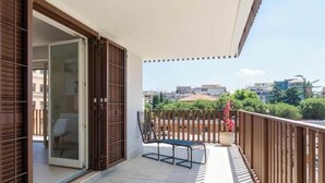 A balcony with a wooden railing, a bench, and a sliding glass door leading to an interior space. - Pigneto Rooftop: Elegant Two-Level Penthouse with Spacious Terraces (Roma)