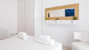 A modern hotel room with a large bed, a wardrobe, a mirror with a wooden frame, and a small shelf with plants. - Pigneto Rooftop: Elegant Two-Level Penthouse with Spacious Terraces (Roma)