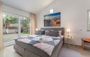 Ein Schlafzimmer mit einem großen Bett, Blick ins Freie, einem Bild an der Wand und einem kleinen Tisch mit einer Lampe.