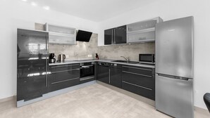 Una cocina moderna con electrodomésticos de acero inoxidable, un televisor de pantalla plana y un lavavajillas.