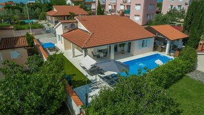 Un edificio residencial con piscina, mobiliario exterior y una zona de patio techada.