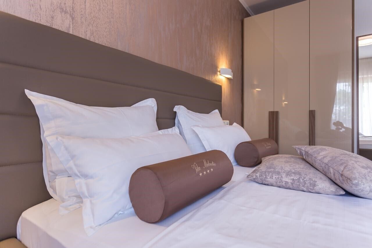 A hotel room with a large bed, a headboard, a bedside table, and a mirror.