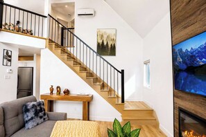 Ein modernes Wohnzimmer mit Treppe, Flachbildfernseher und Kamin.