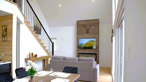 Una sala de estar moderna con comedor, escalera y televisor montado.