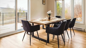 Un comedor con una mesa de madera, sillas negras y un jarrón de flores.