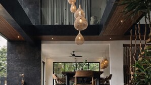 Un interior moderno con comedor, una escalera y una lámpara colgante.