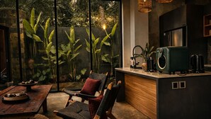 Una cocina moderna con barra, mobiliario de madera y ventanas amplias con vistas a un jardín.