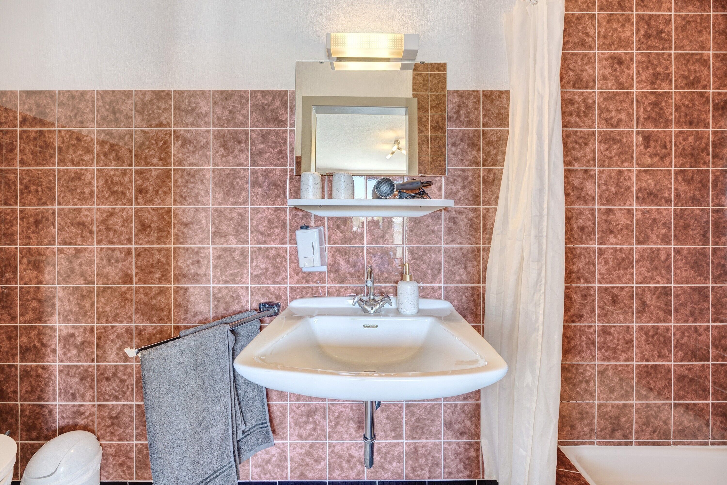 Ein Badezimmer mit Waschbecken, Spiegel und Duschvorhang.
