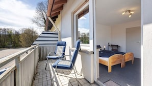 A balcony with two blue chairs, a wooden bed, and a view of the outdoors. - Room 3 with Balcony for 2 Guests (Extertal)
