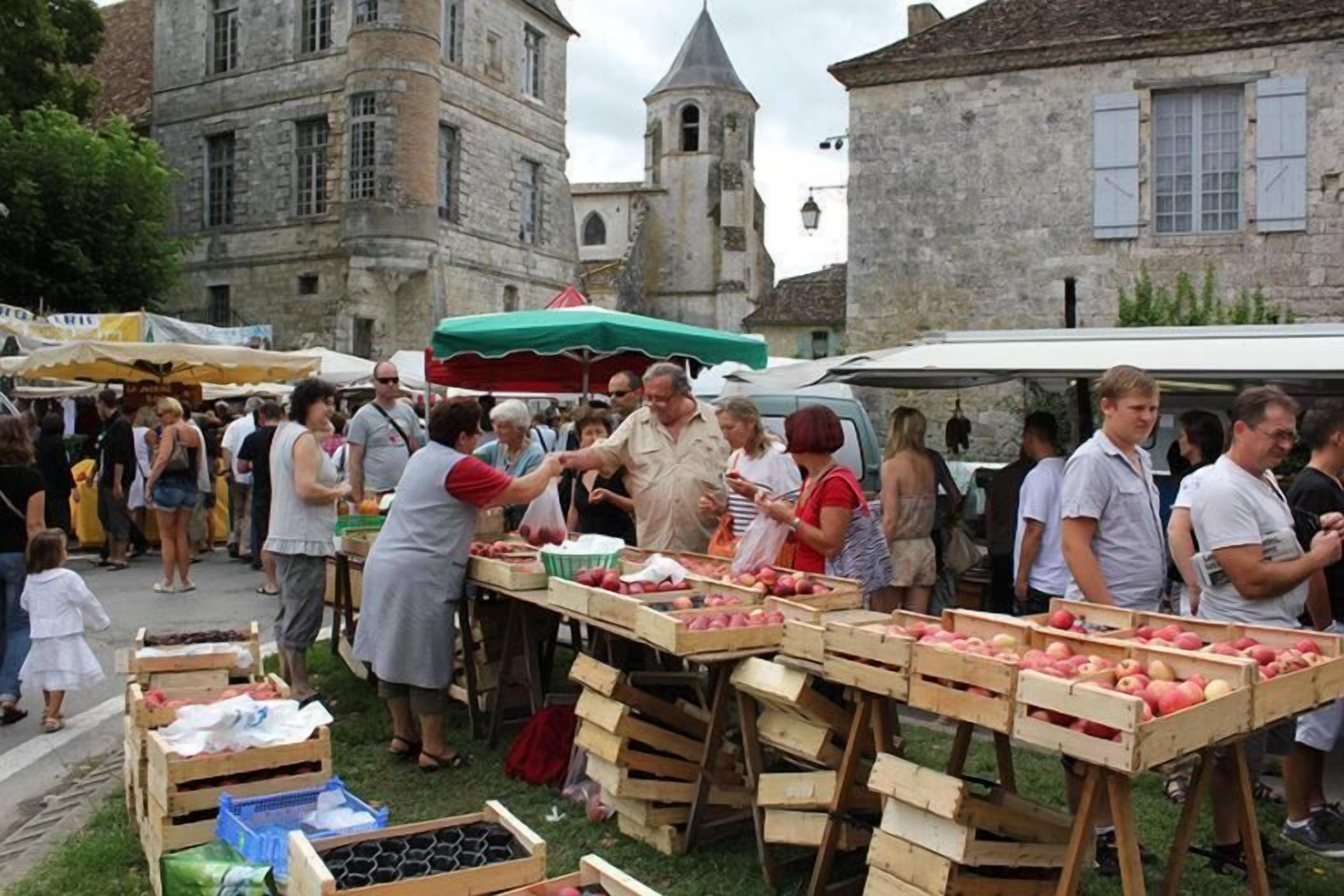 Ein Markt mit Holzkisten voller Äpfeln und einem historischen Gebäude im Hintergrund.
