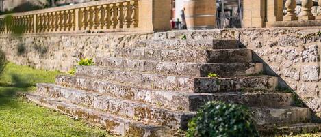 Steinelemente bilden eine Treppe, die zu einem Gebäude mit Steinbalustrade führt.