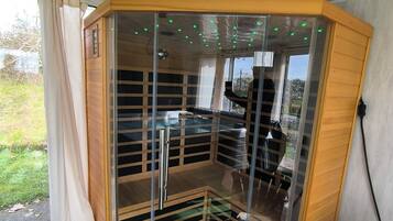 A corner sauna with a glass enclosure, a wooden bench, and a view of the outdoors.