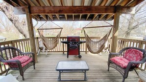Une terrasse couverte, aménagée avec des meubles en osier, un barbecue et des hamacs.