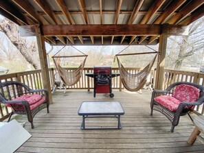 Eine überdachte Terrasse mit Korbmöbeln, einem Grill und Hängematten.
