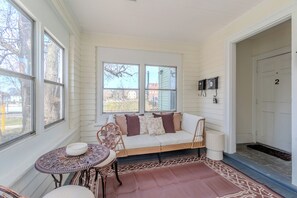 A sunroom with a sofa, a table, and a chair, large windows, and a door with the number 2. - Peaceful 8-bed, 5-bedroom house in charming Somerville (Somerville)
