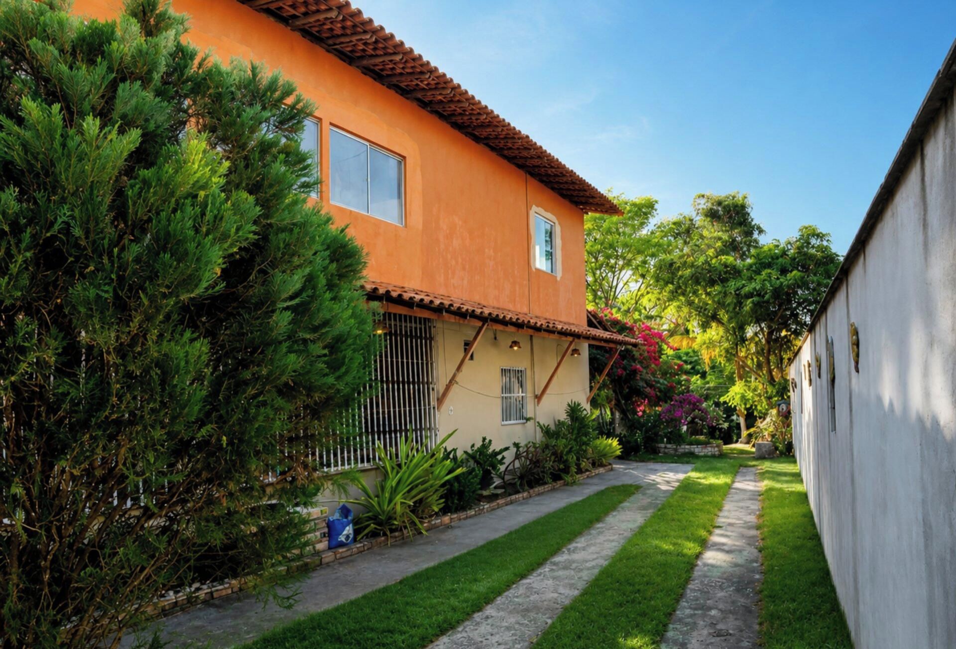 A two-story house with a tiled roof, a front yard with a pathway, and a variety of plants.