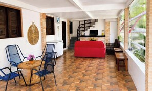 Un espacio habitable compacto con comedor, un sofá rojo y una escalera que sube a un nivel superior.