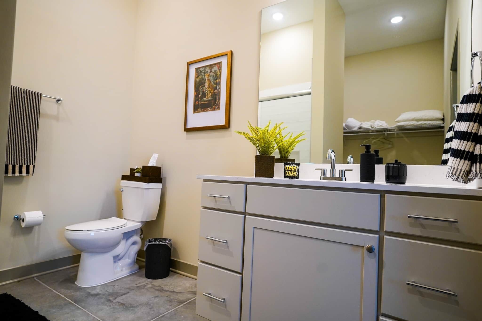 A bathroom with a toilet, sink, mirror, and towel rack.