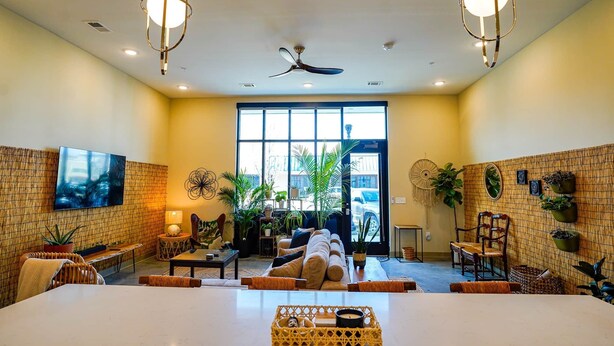 A spacious room with a large bed, a ceiling fan, and a TV mounted on the wall.