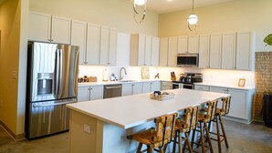 A modern kitchen with a central island, stainless steel appliances, and a large island with bar stools.