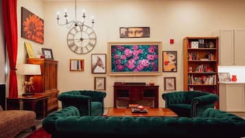 Una sala de estar con dos sofás verdes, una mesa de centro de madera, un reloj grande y una estantería.