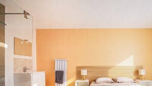 Een hotelkamer met een bed, nachtkastjes, een radiator aan de muur en een raam met gordijnen.