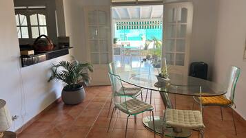 A dining area with a glass table and chairs, a potted plant, and a view of the outdoors.