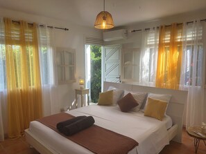 Un dormitorio con cama, mesita de noche, lámpara y cortinas.