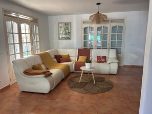 A living room with two white sofas, a round woven rug, and a potted plant. - VILLA CLIANE (Baie-Mahault)