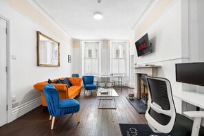 A modern living room with a sofa, chairs, a coffee table, a fireplace, and a TV mounted on the wall. - Oriental Eight | By My Getaways (Brighton)