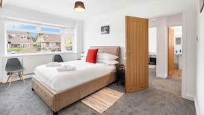 A bedroom with a bed, a window, a door, and a view of the outside. - Coral Haven With Parking | By My Getaways (Worthing)