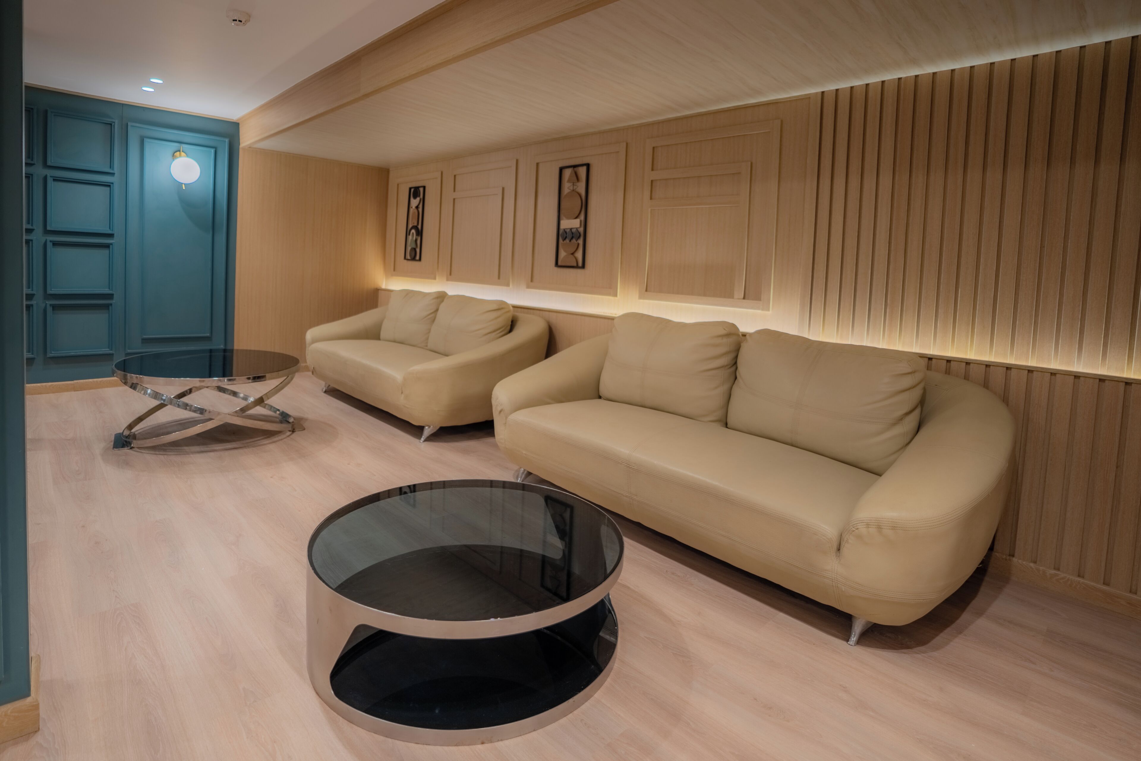 Ein modernes Wohnzimmer mit zwei Sofas, einem Glastisch und Holzvertäfelung an den Wänden.